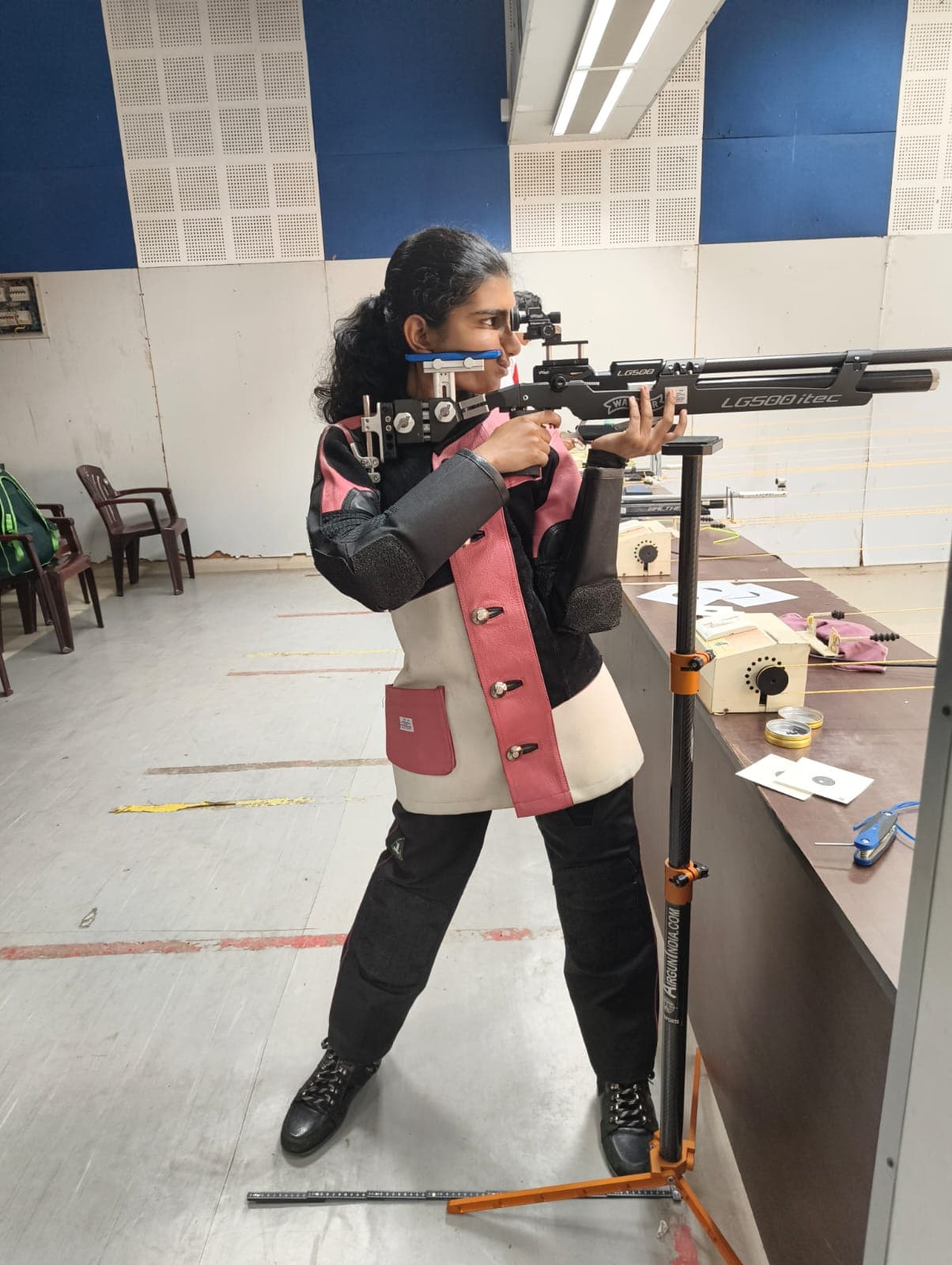 Brahmitha G in standing position, sighting down her air rifle at the practice range